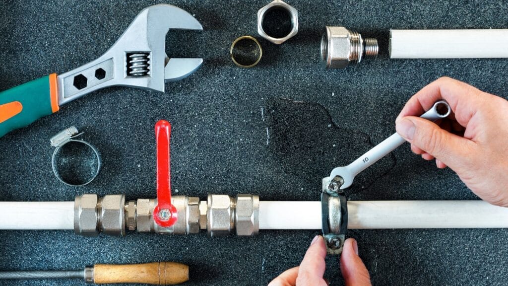 Plumber repairing a pipe valve with an adjustable wrench in Riverview