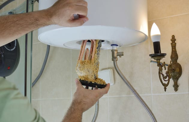 Technician removing mineral buildup from a water heater in Riverview