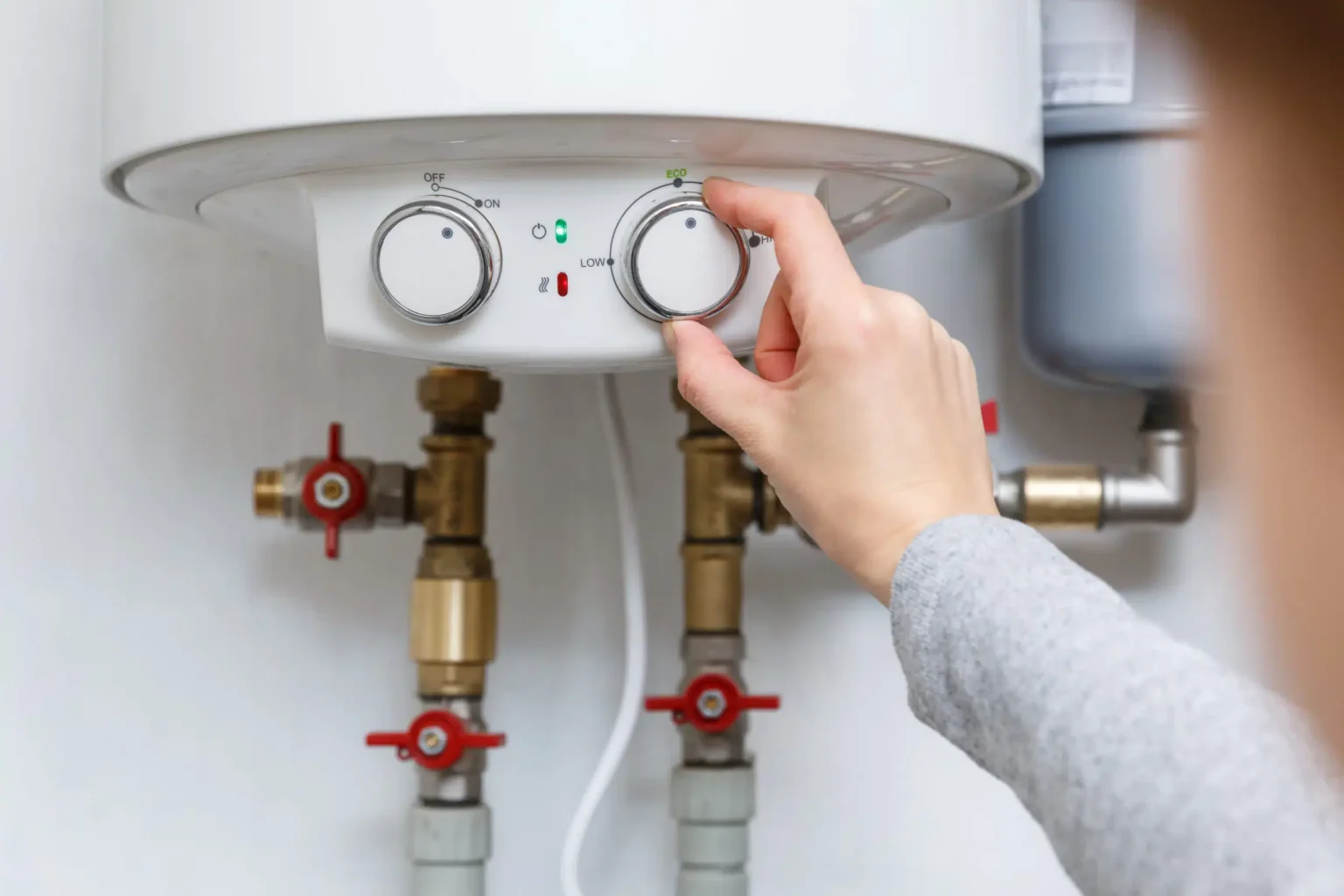 Homeowner adjusting the temperature controls on a water heater in Riverview